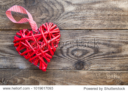red wicker heart with ribbon on a wooden background