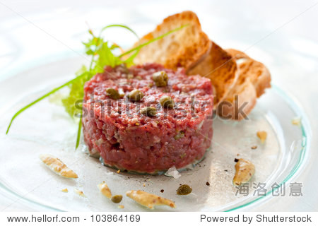 close up of beef tartar with capers and small toasts.