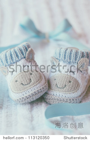 为蓝色背景上的男孩针织婴儿鞋。生日贺卡婴儿