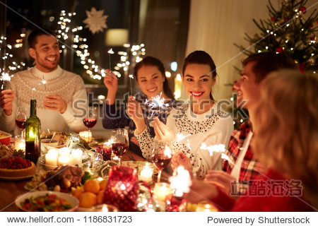 winter holidays and people concept - happy friends with sparklers celebrating christmas at home feast