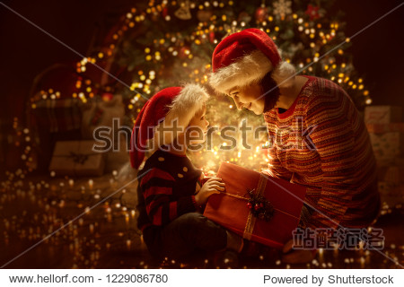 Family open Christmas Lighting Present Gift Box front of Xmas Tree Happy Mother with Baby Child in Magic Night