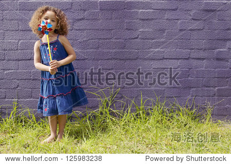 a blue dress blowing a pinwheel standing barefoot on grassy