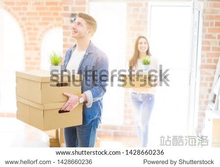 beautiful young couple smiling in love holding cardboard boxes