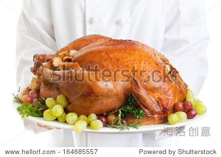 chef serving a stuffed turkey garnished with grapes.