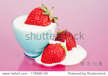 three strawberries in blue cup with yogurt spill