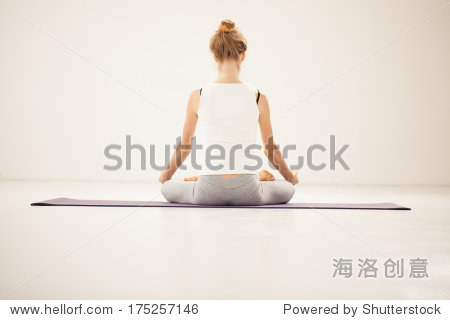 back view of a woman meditationg in the lotus pose.
