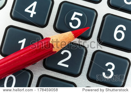 一个红笔在一个计算器。节省成本,费用和预算
