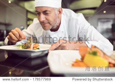 closeup of a concentrated male chef garnishing food in the