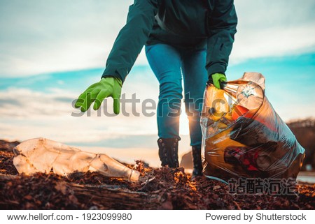 A volunteer collects garbage on a muddy beach. Close-up. The concept of Earth Day. Bottom view.