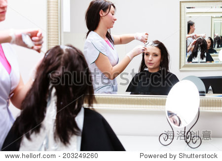 professional female hairdresser applying color to
