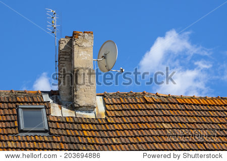satellite antenna on the chimney roof of the house with tiles.