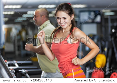 sportive woman and man are running on treadmill in a gym