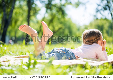 rear view of little girl lying in summer park