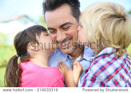 portrait of kids giving a kiss to their daddy