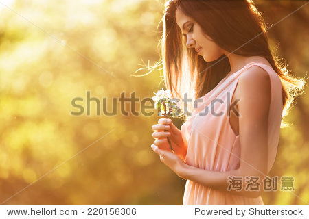 beautiful girl holding a flower at sunset