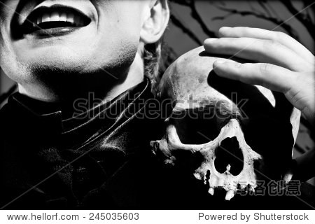 一个年轻人穿着黑色衣服,手里拿着一个头骨。
