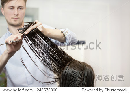 handsome hairdresser making a haircut for a  girl