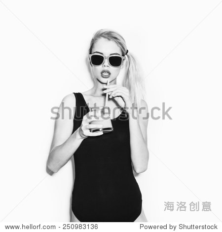 苗条的金发美女在黑体和橙汁喝鸡尾酒。情感。