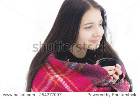 cup of hot beverage.beautiful young brunette woman with a hat
