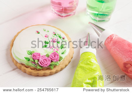white icing cookie with painted roses on white background and