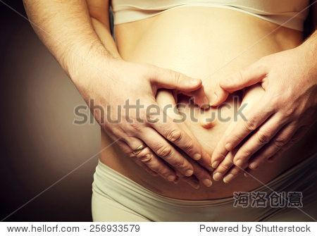 孕妇的肚子用手指心的象征。年轻漂亮的孕妇和