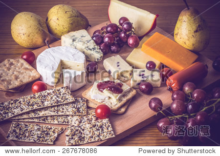 cheese platter with crackers and grapes on wooden board.
