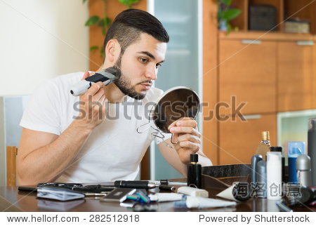 young american guy looking at mirror and shaving