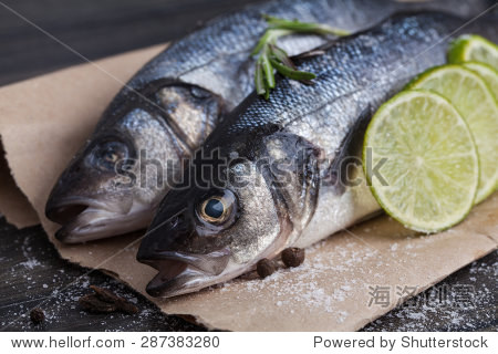 raw seabass fish on the wooden board with vegetables