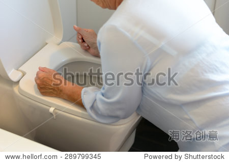 woman getting sick and vomiting over a toilet bowl kneeling down