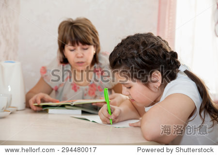 成熟的母亲在家里帮助她的孩子对家庭作业没什