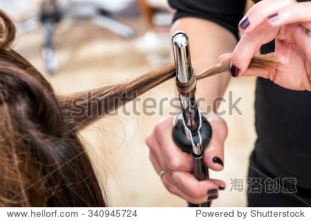 hairstylist using a curling iron to firm ringlets