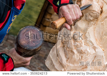 hands of sculptor and hammer detail while carving wood
