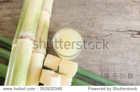 freshly squeezed sugar cane juice in glass with cut pieces cane