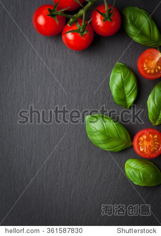halved cherry tomatoes and basil leaves on black