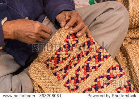 hands of a craftsman weaving handicraft items made of jute