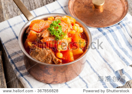stew of beef with vegetables in a copper pot closeup horizontal