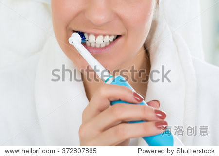 close-up of a young woman in bathrobe brushing teeth with