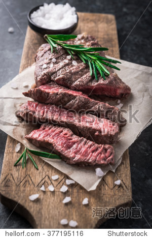 grilled beef steak with rosemary and salt on cutting board
