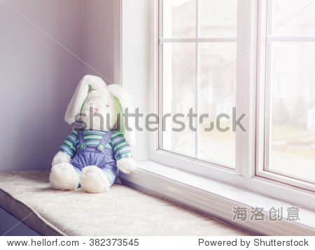 soft plush bunny toy with large ears sitting on windowsill near
