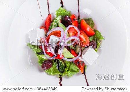 greek salad with fresh vegetables feta cheese olives and sauce.