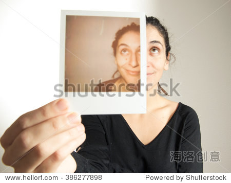 年轻女子拿着即时照片重叠的一半的一半的她的