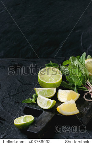 sliced lime and lemons with bunch of fresh mint on black wooden