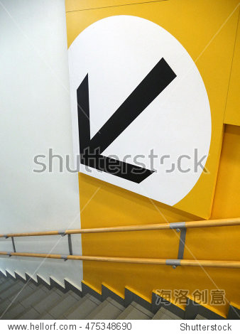downstairs black arrow in white circle on yellow wall