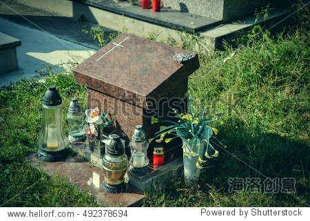 votive candles lantern and flowers on tomb stones in graveyard.