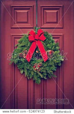 christmas wreath hanging on a red wooden door.