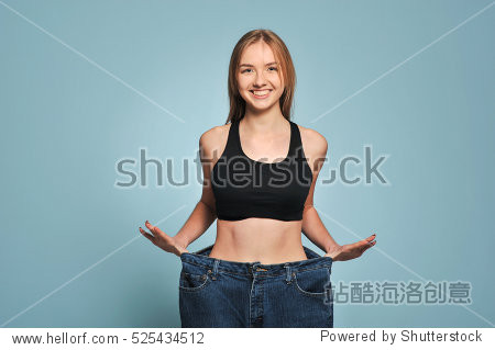 fit young woman in loose jeans after losing weight isolated on