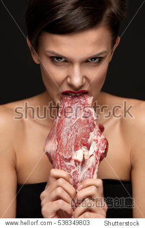 hungry woman with red lips ripping raw meat with teeth.