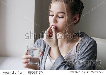 young beautiful girl or woman to take a pill with a glass of