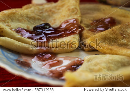 pancakes with cherry jam and cutlery on a red background