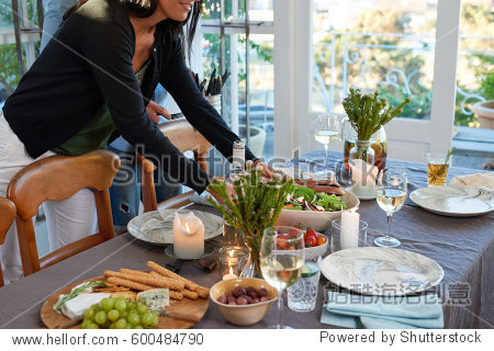 hostess laying down serving food on dinner table preparing for
